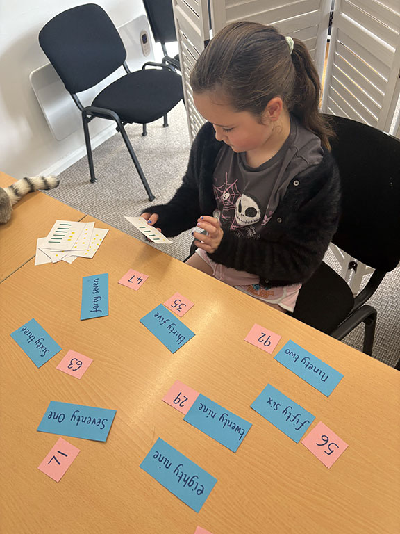 A child works with colourful word and number cards during a Next Step learning session