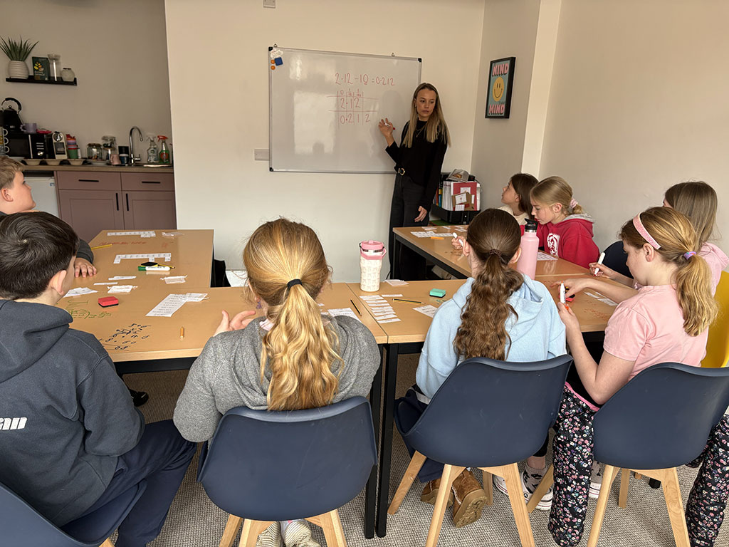 Small group of pupils following a maths explanation on the whiteboard during SATs support at EH Education.